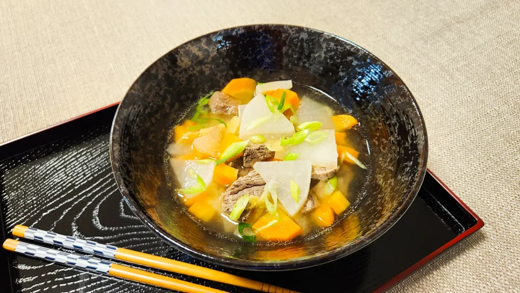 Close-up of beef and ginger soup with daikon radish and carrots