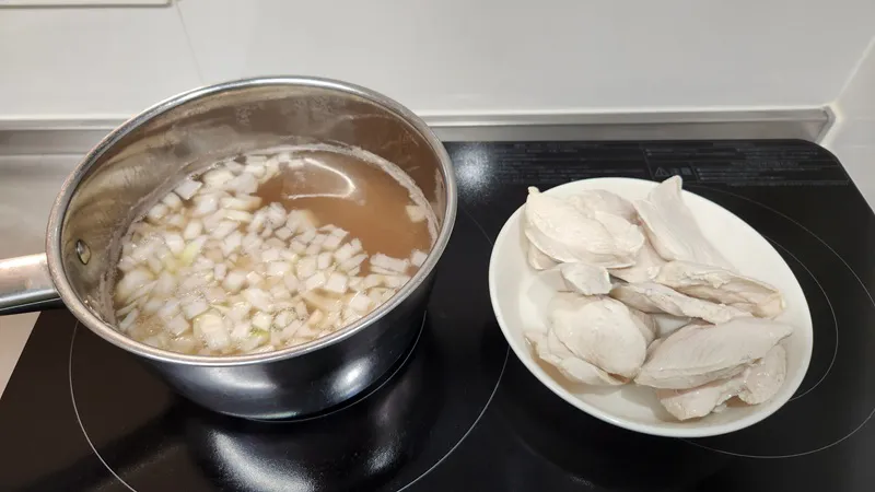 鶏スープを作るために、角切りの玉ねぎと一緒に鍋で煮ている鶏むね肉と軽いだし。
