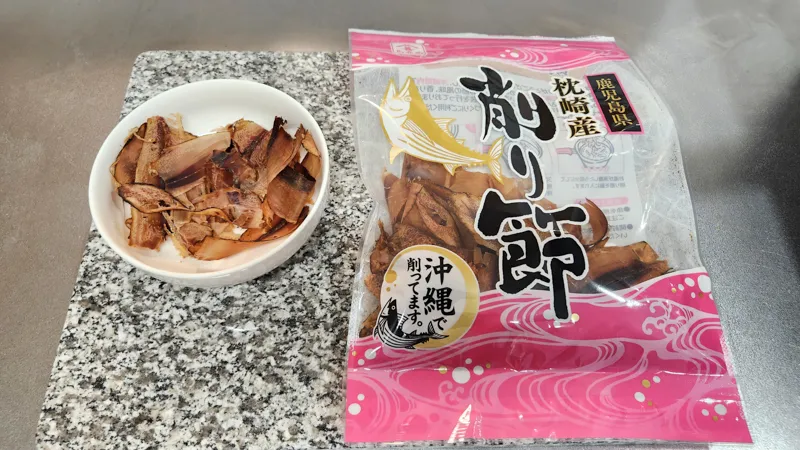 Dried bonito flakes placed in a small bowl next to the original Japanese package