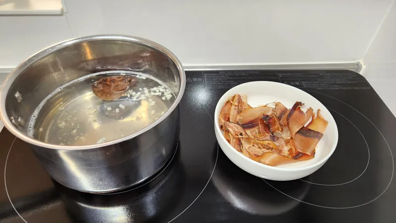Dried bonito flakes and dried shiitake mushroom soaking in water in a saucepan