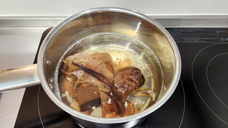 Bonito flakes and dried shiitake mushroom simmering gently in a saucepan
