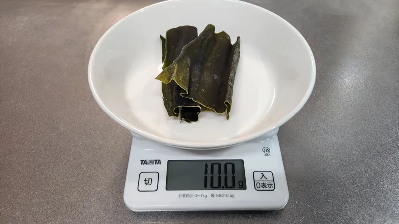 キッチンスケールで量られた乾燥昆布。
加熱前に冷水に浸した乾燥昆布。
鰹節の横で水に浸された昆布。
鶏スープを作るために、鍋の昆布だしに加えられた鰹節。
熱湯で下茹でされている鶏肉。
鍋に入った澄んだ鰹だし。
鍋で静かに沸いている鰹だし。
乾燥した赤豆と緑豆のボウルの横で煮立つだし。
角切りの玉ねぎと一緒に静かに煮ている軽い鰹だし。
鶏スープを作るために、角切りの玉ねぎと一緒に鍋で煮ている鶏むね肉と軽いだし。
コンロの上で、野菜入りのだしの中で鶏肉を煮ている調理中の鶏スープ。
ボウルに入った丸ごとのシークヮーサー。
野菜と豆と一緒に鍋で煮ている鶏スープ。
日本の家庭料理用に包装された乾燥小豆。
キッチンの作業台の上に置かれた新鮮なチンゲン菜。
日本のだしに使われる包装された乾燥昆布。
