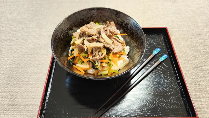 Japanese ginger beef stir fry served over rice with vegetables on a tray