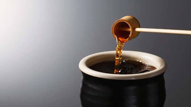 Soy sauce being poured into a ceramic container