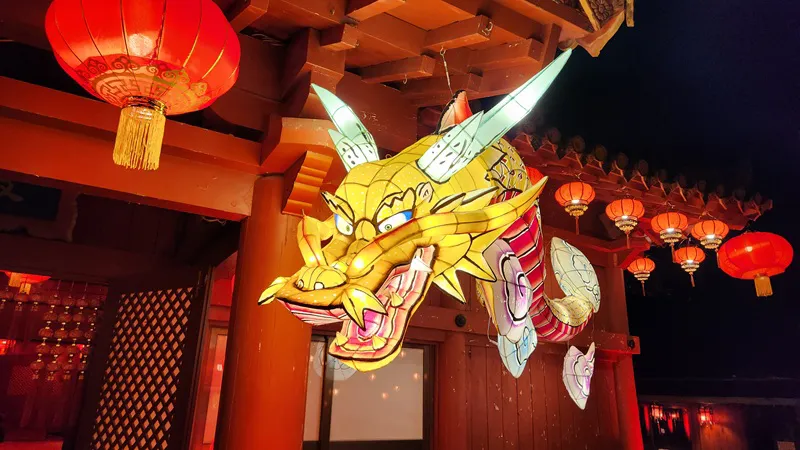 Illuminated dragon lantern hanging under a traditional wooden building