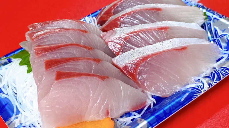 Sliced raw fish sashimi arranged on a tray with garnish
