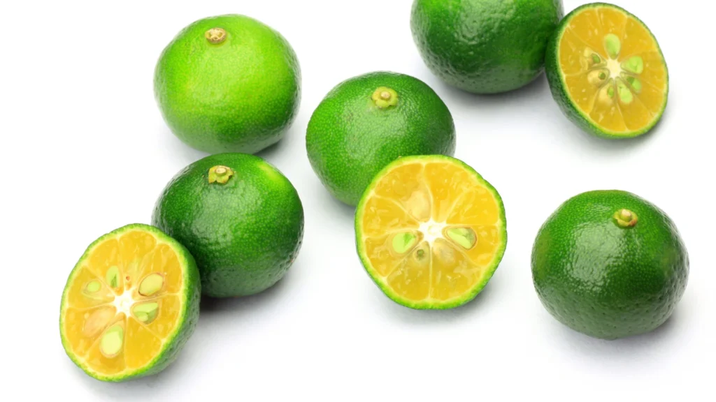 Whole and halved green shikuwasa citrus fruits showing yellow pulp