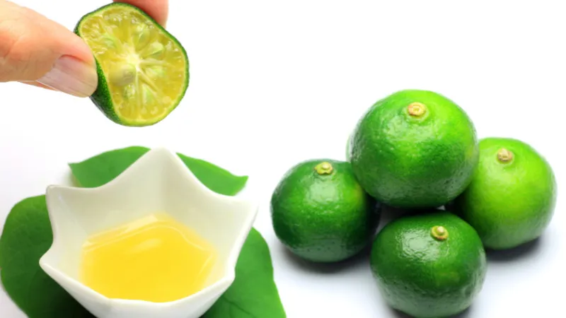 Main pressant un shikuwasa au-dessus d’un petit bol de jus.
