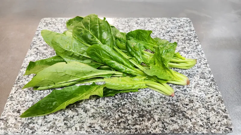 Fresh spinach with stems and leaves on a cutting board