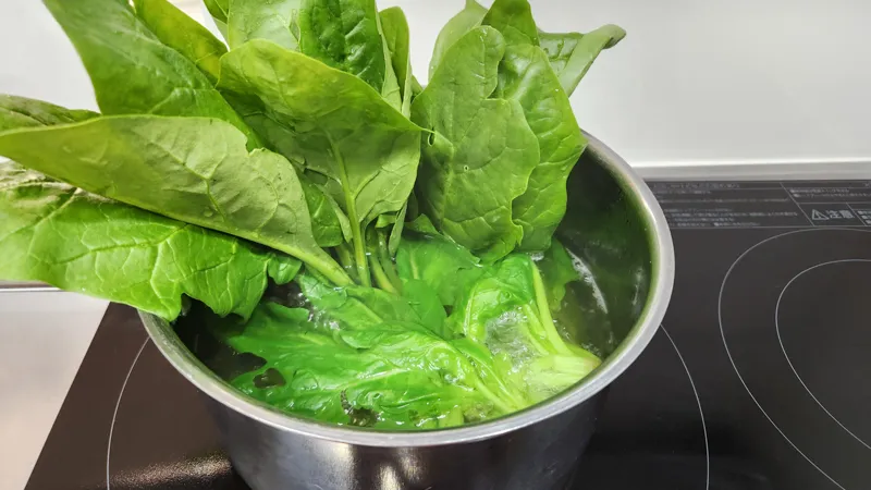 Fresh spinach being blanched in boiling water in a saucepan