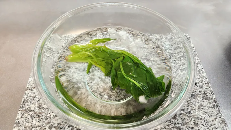 Blanched spinach cooling in a bowl of ice water