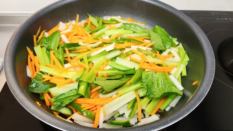 Komatsuna, carrot, daikon, and green pepper cooking together in a pan