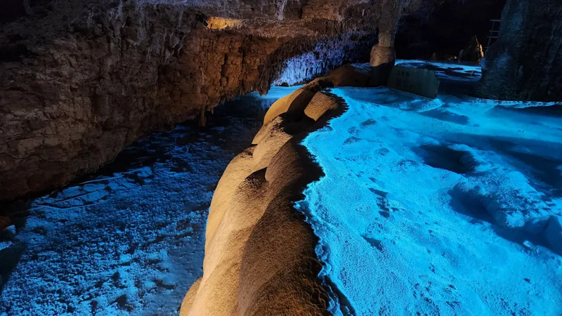 Gently curved limestone formations lit by blue light in Okinawa World cave
