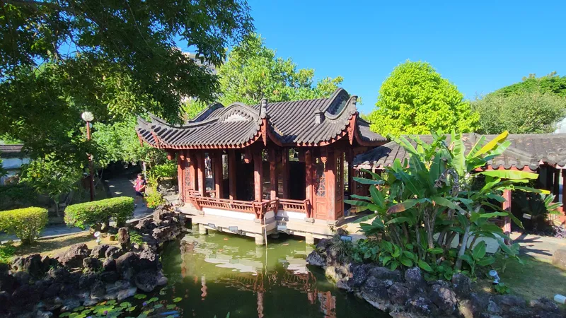 Traditional Chinese pavilion built over a pond surrounded by greenery in Fukushuen Garden Okinawa