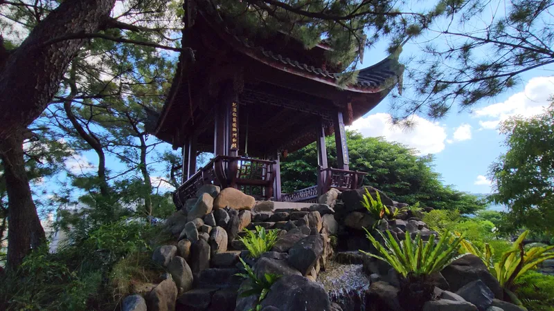 Chinese style pavilion on a rocky hill surrounded by trees in Fukushuen Garden Okinawa