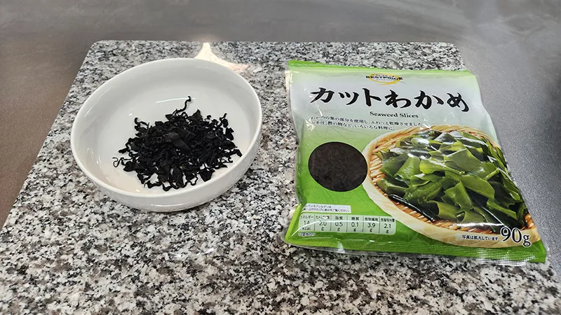 Dried wakame seaweed in a bowl next to packaging