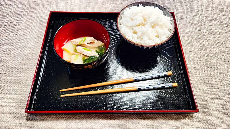 Serving tray with bluefin tuna soup, bowl of white rice and chopsticks