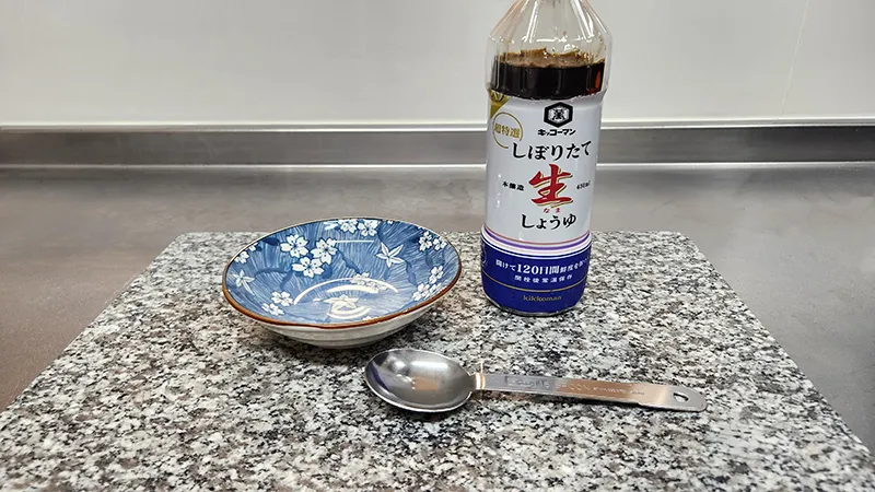 Bottle of soy sauce with spoon and small dish